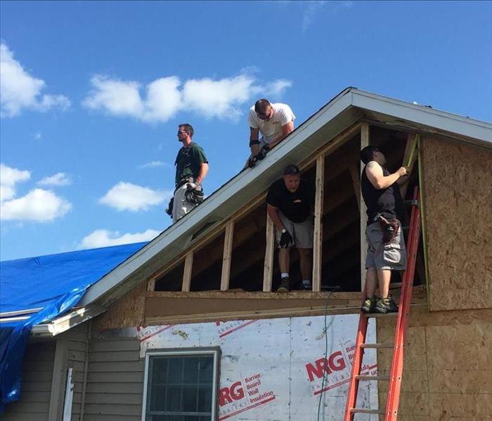 Crew working on a roof and exterior of a home.